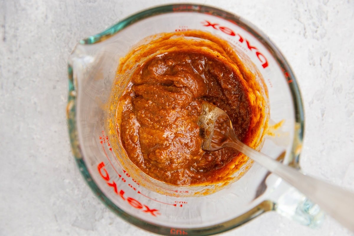 Measuring cup full of Thai peanut sauce for chicken wraps.