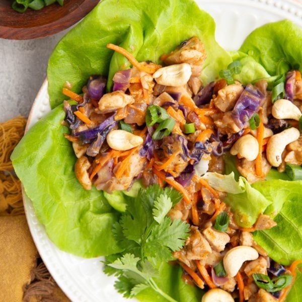 Plate of Thai Chicken Lettuce wraps with a bowl of green onions to the side.