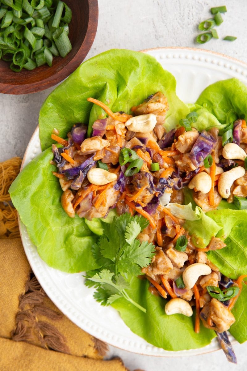 Plate of Thai Chicken Lettuce wraps with a bowl of green onions to the side.