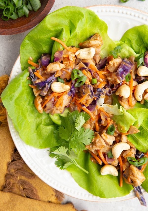 Thai Chicken Lettuce Wraps on a plate with fresh cilantro and cashews.