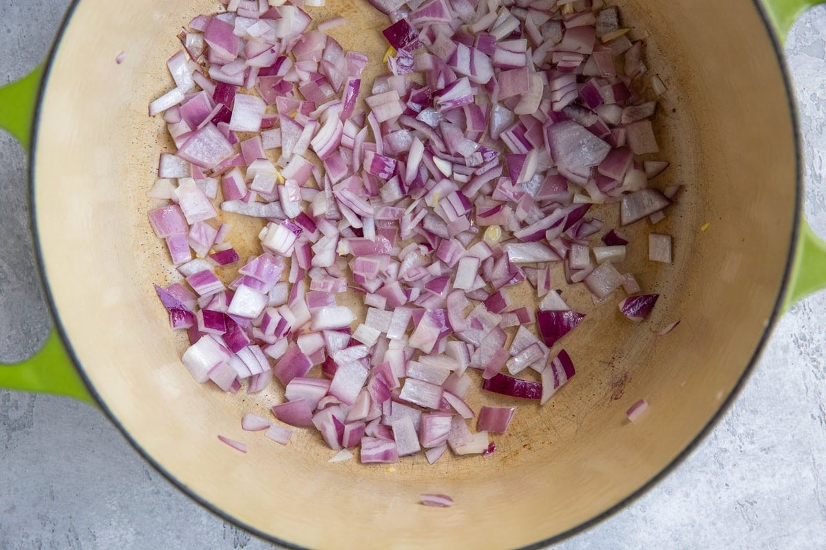 Red onions cooking in a large pot.