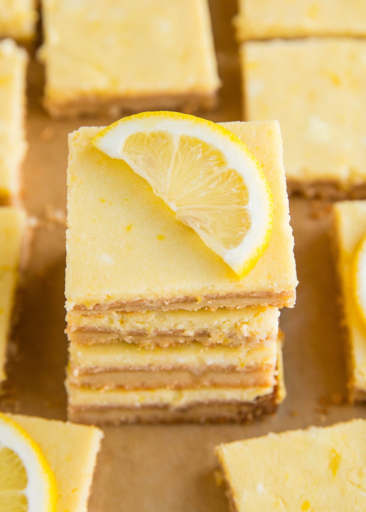 Stack of four lemon bars with a slice of lemon on top. Ready to eat.