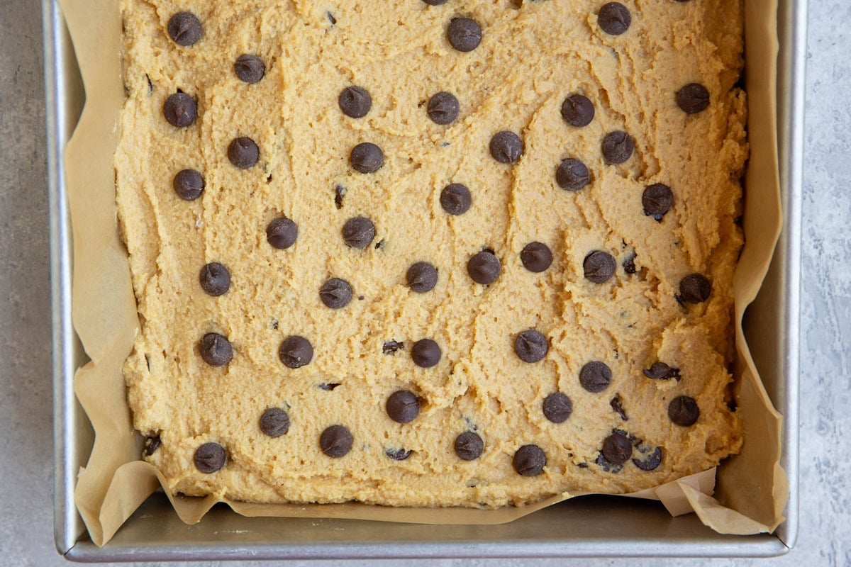 Baking dish with peanut butter bar dough spread inside with chocolate chips on top.