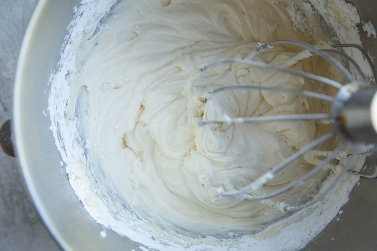 Stand mixer with cream cheese frosting inside with the whisk attachment