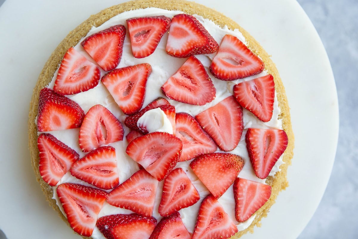 Vanilla cake frosted with strawberries on top.