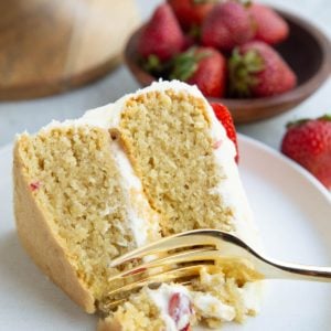 Fork taking a bite of vanilla layer cake.