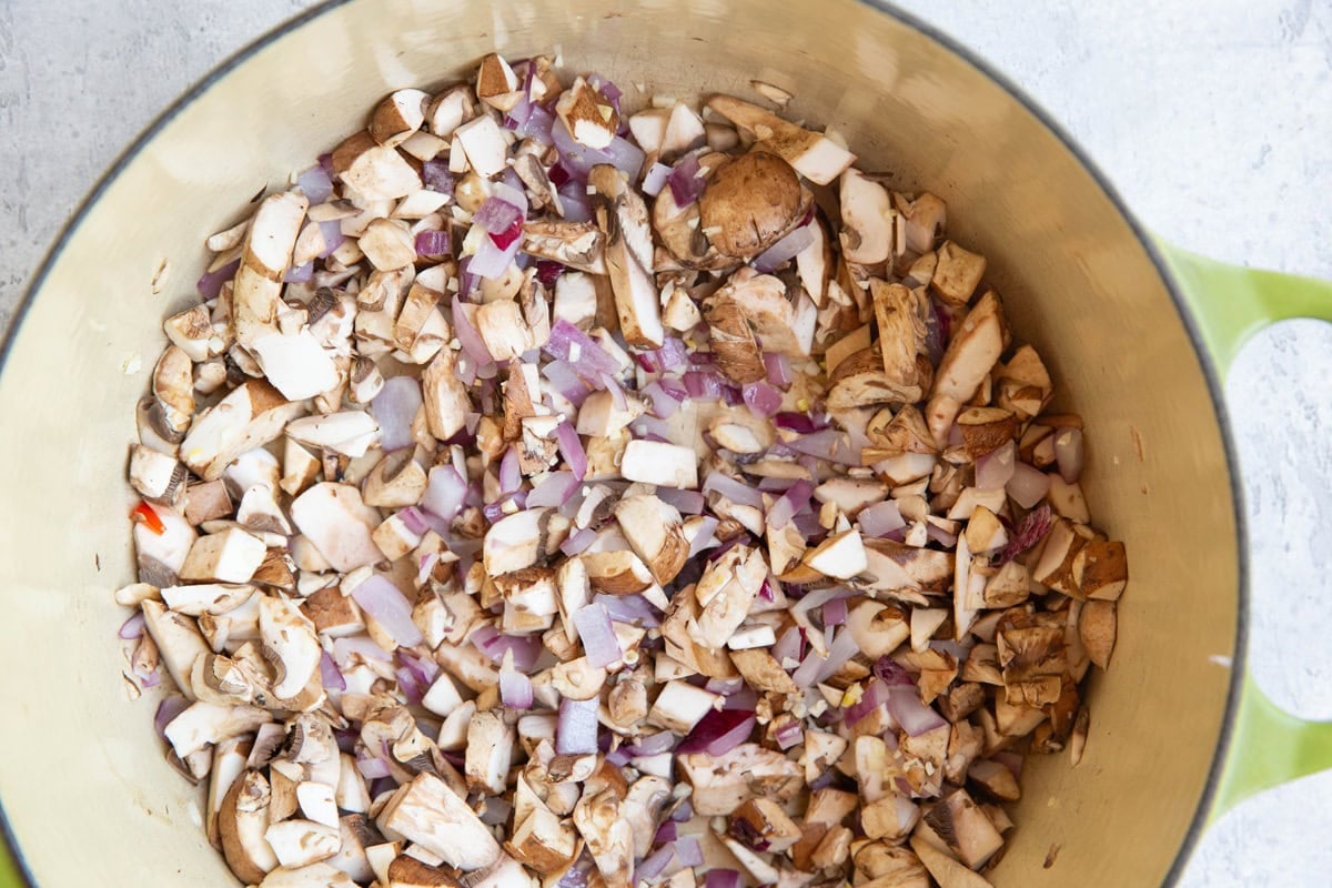 Onions, mushrooms, and garlic cooking in a large pot.