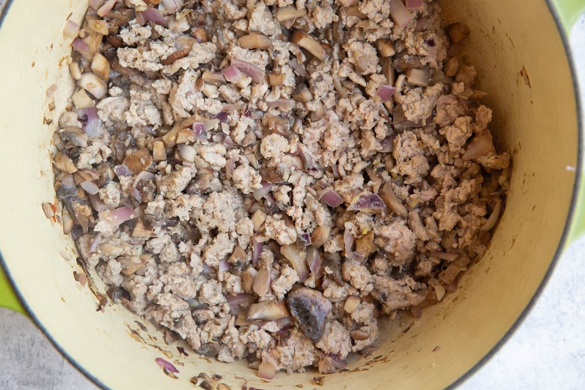 Ground turkey, mushrooms, onion, and garlic cooking in a large pot.