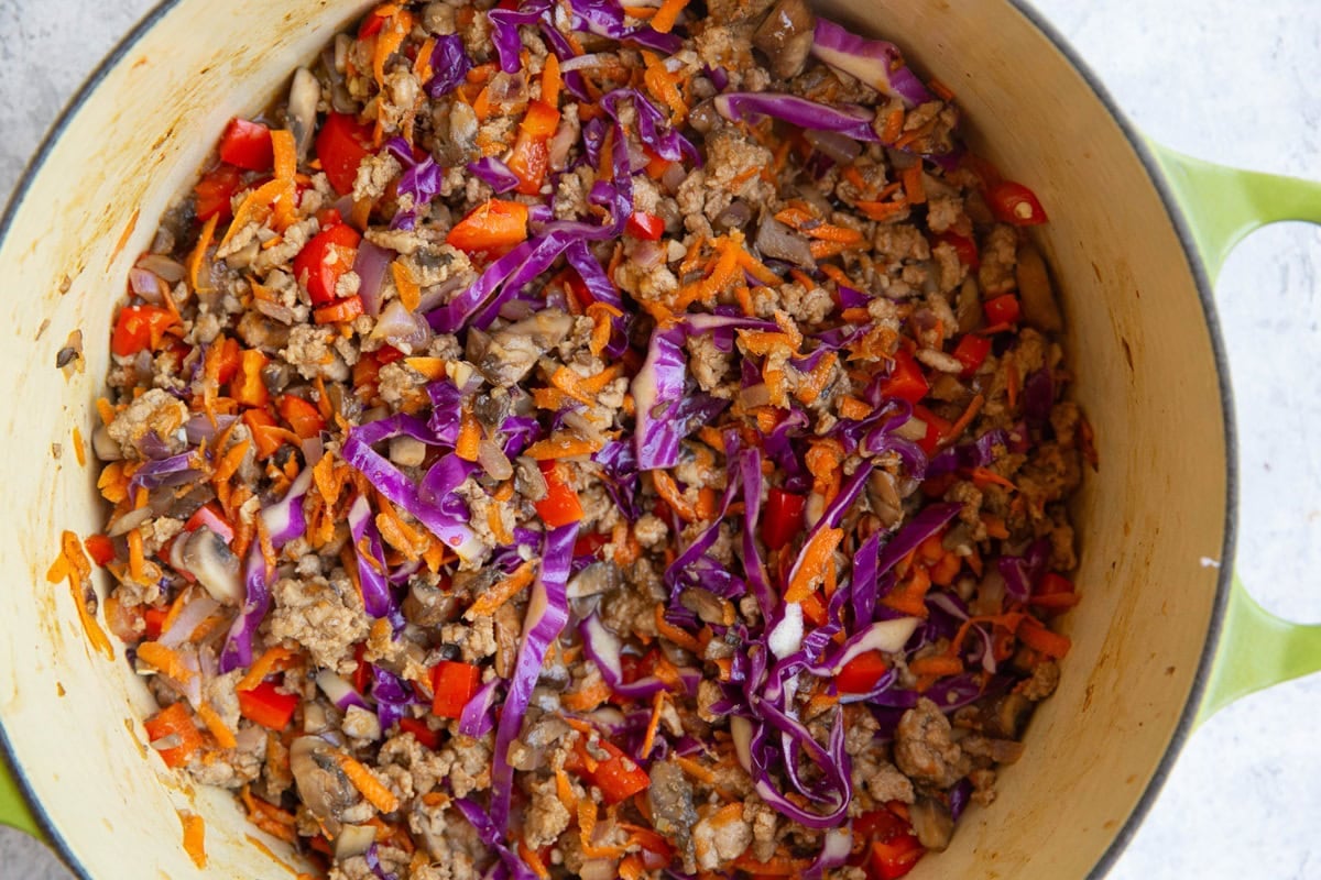 large pot full of ground turkey, cabbage, carrots, bell peppers, and more, to make turkey bowls.