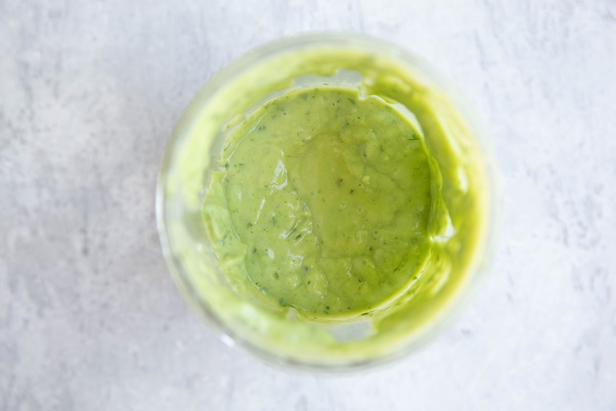 Blended avocado dressing in a small blender, ready to use.