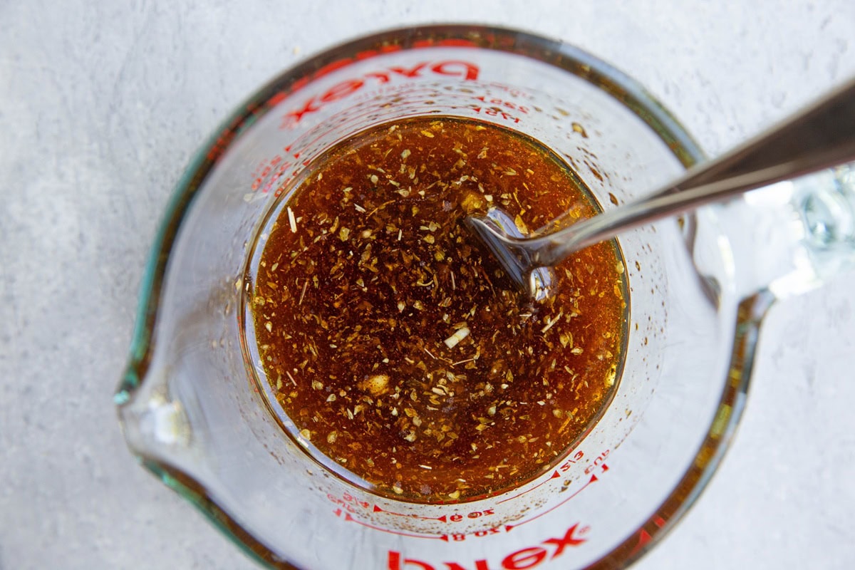 Chicken drumstick marinade stirred up in a measuring cup with a fork. Ready to be used.