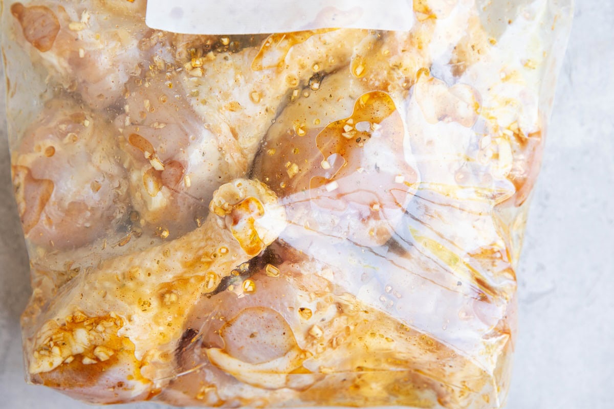 Large zip lock bag full of chicken drumsticks marinating in a delicious marinade.