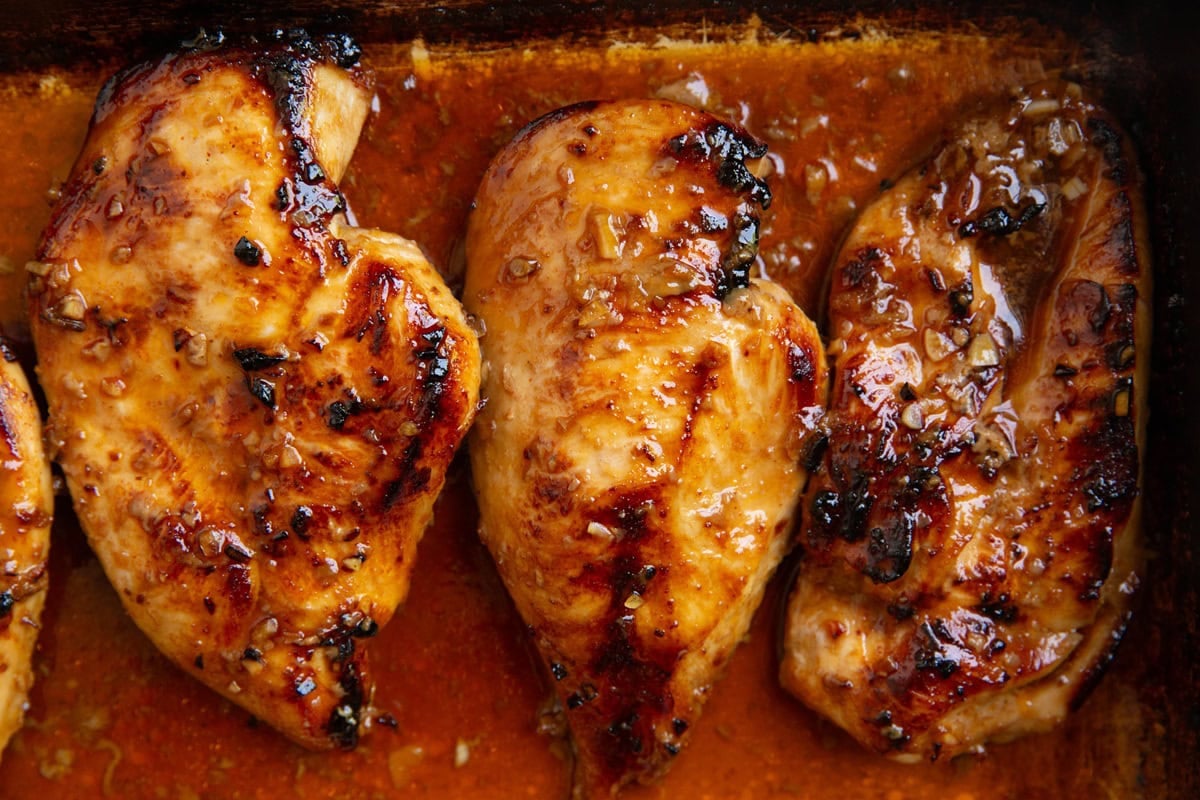 Casserole dish with chicken breasts inside covered in marinade, cooked to perfection.