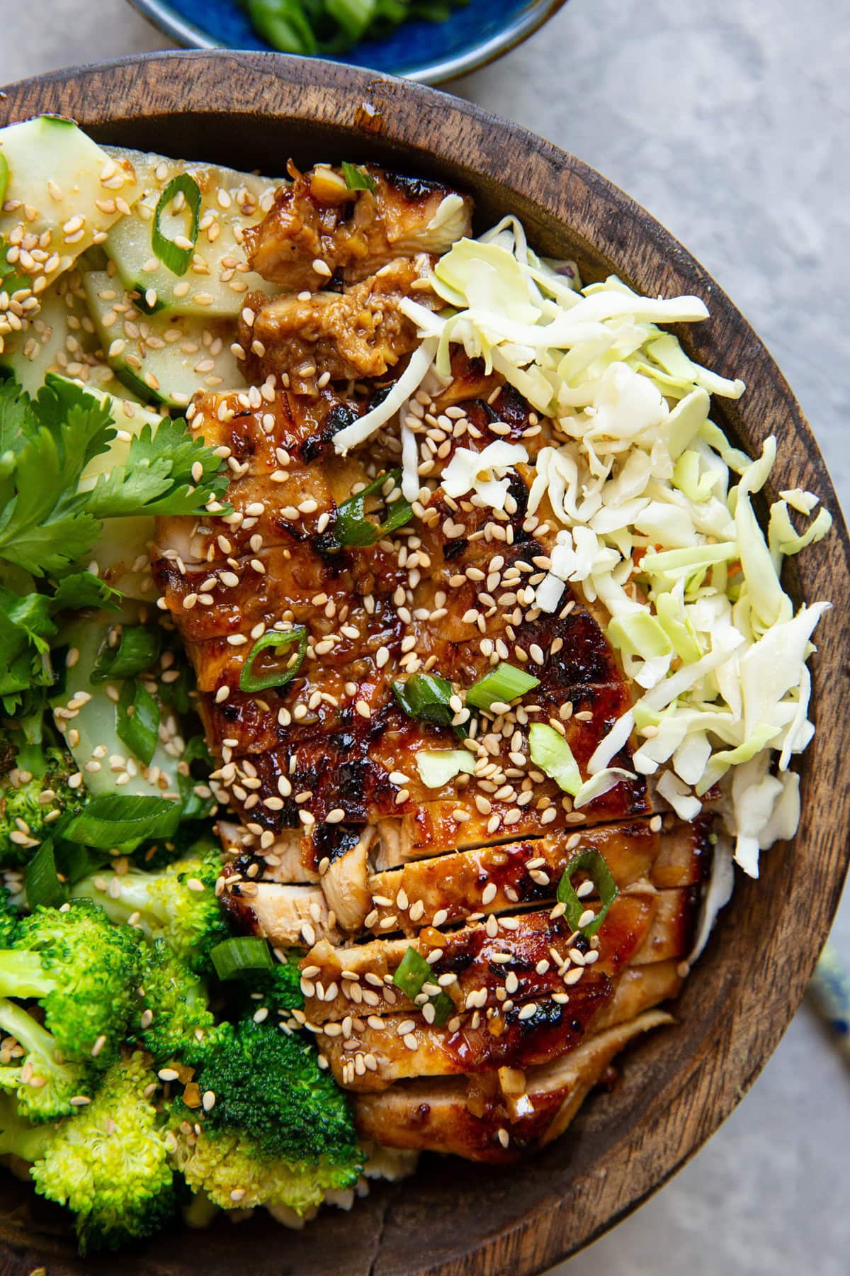 Korean BBQ Chicken in a bowl with fresh vegetables, rice, and sauce for a healthy meal.