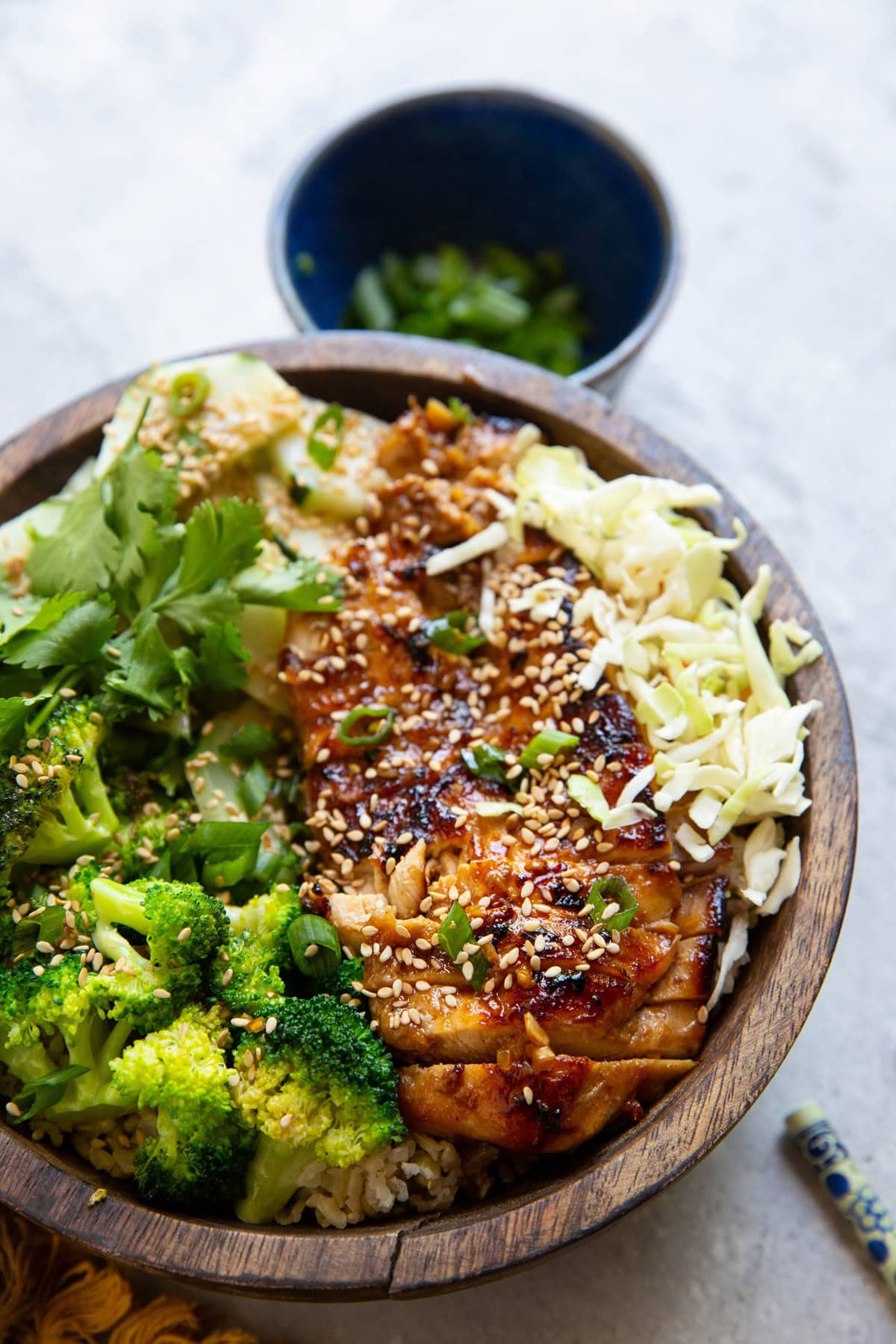 Korean chicken cut into slices in a bowl with steamed broccoli, cabbage, rice, and more.