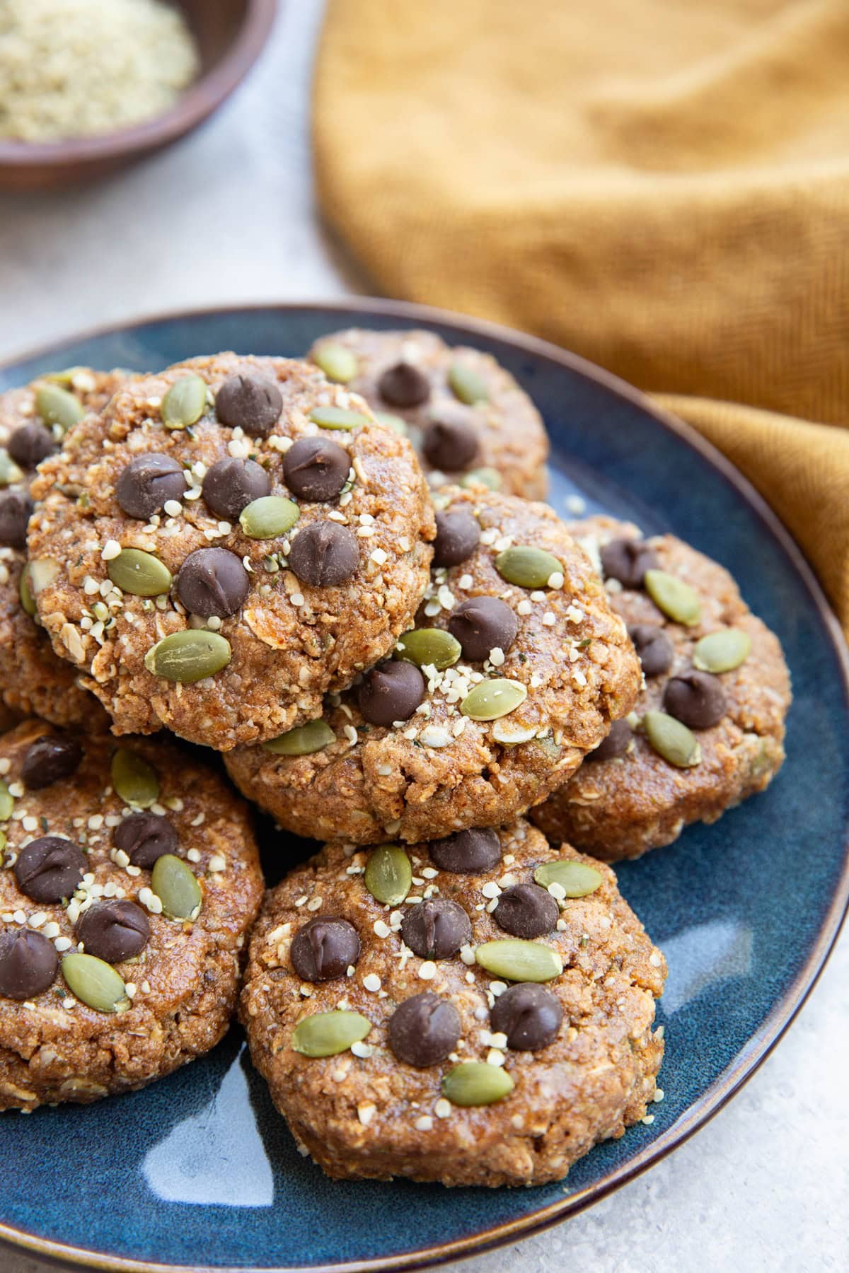 No bake breakfast cookies sitting in a pile on a blue plate with a golden napkin in the background.