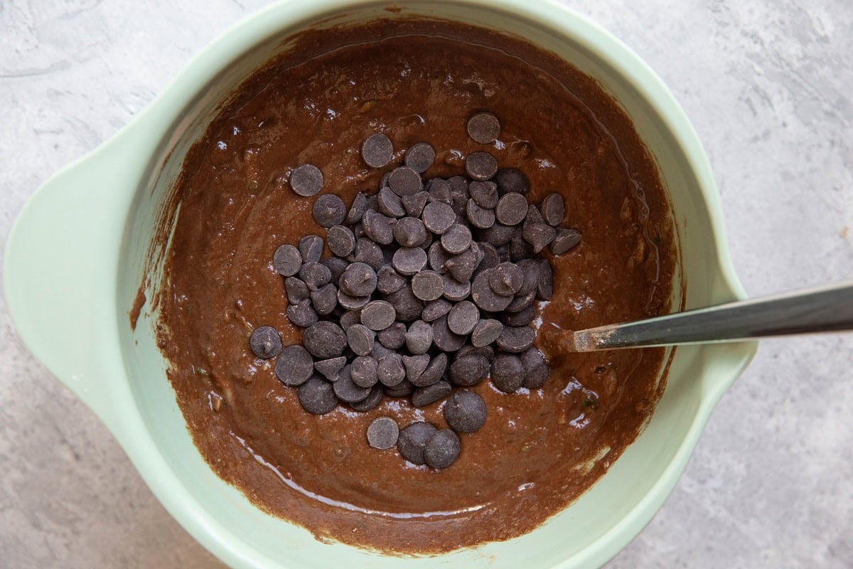 Chocolate chips on top of chocolate zucchini bread batter, ready to be mixed in.