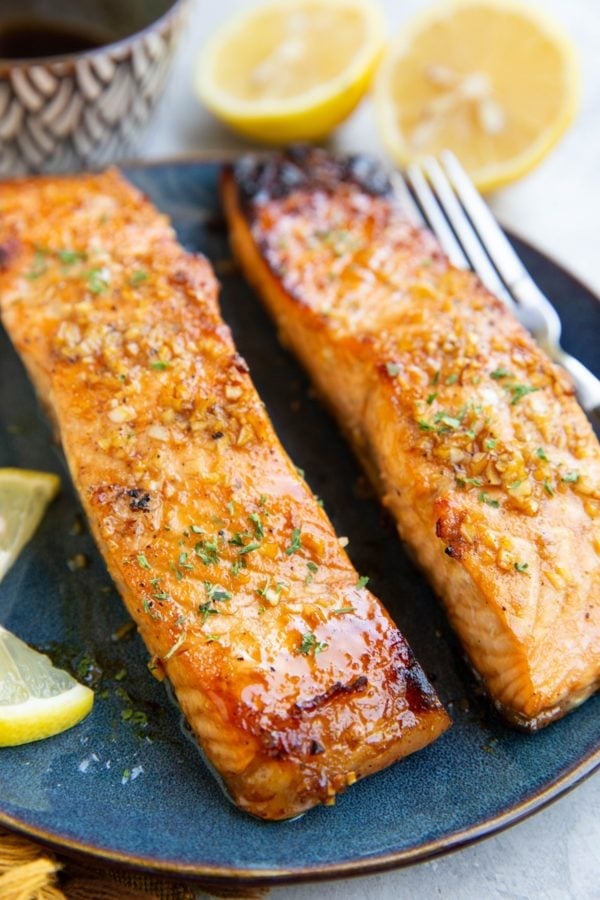 Balsamic glazed salmon on a plate with a fresh lemon in the background and a small bowl of glaze.