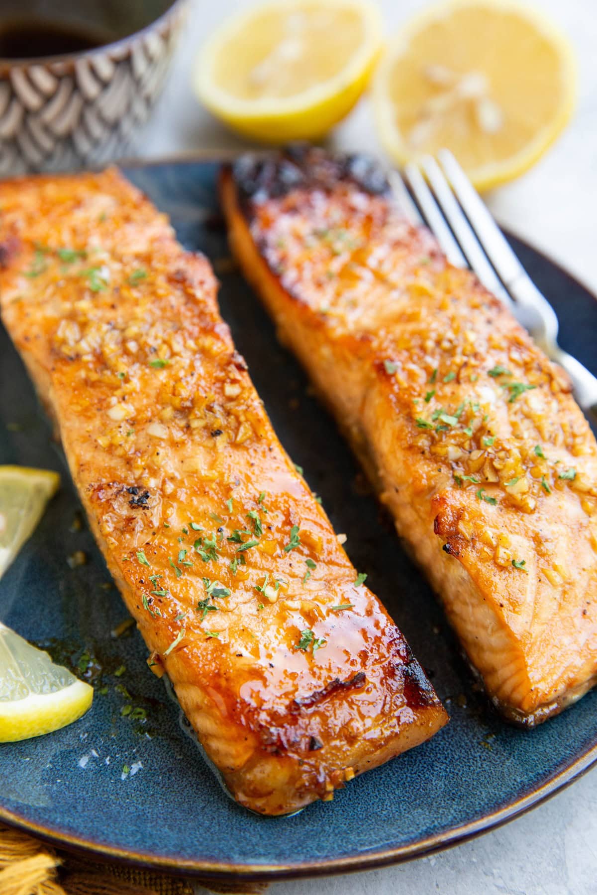 Balsamic glazed salmon on a plate with a fresh lemon in the background and a small bowl of glaze.