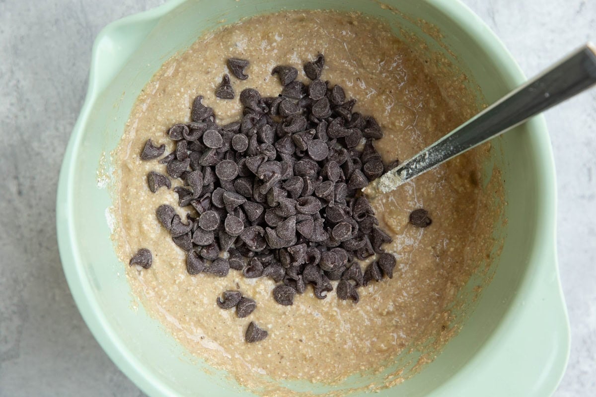Banana oat muffin batter in a mixing bowl with chocolate chips on top, ready to be mixed in.