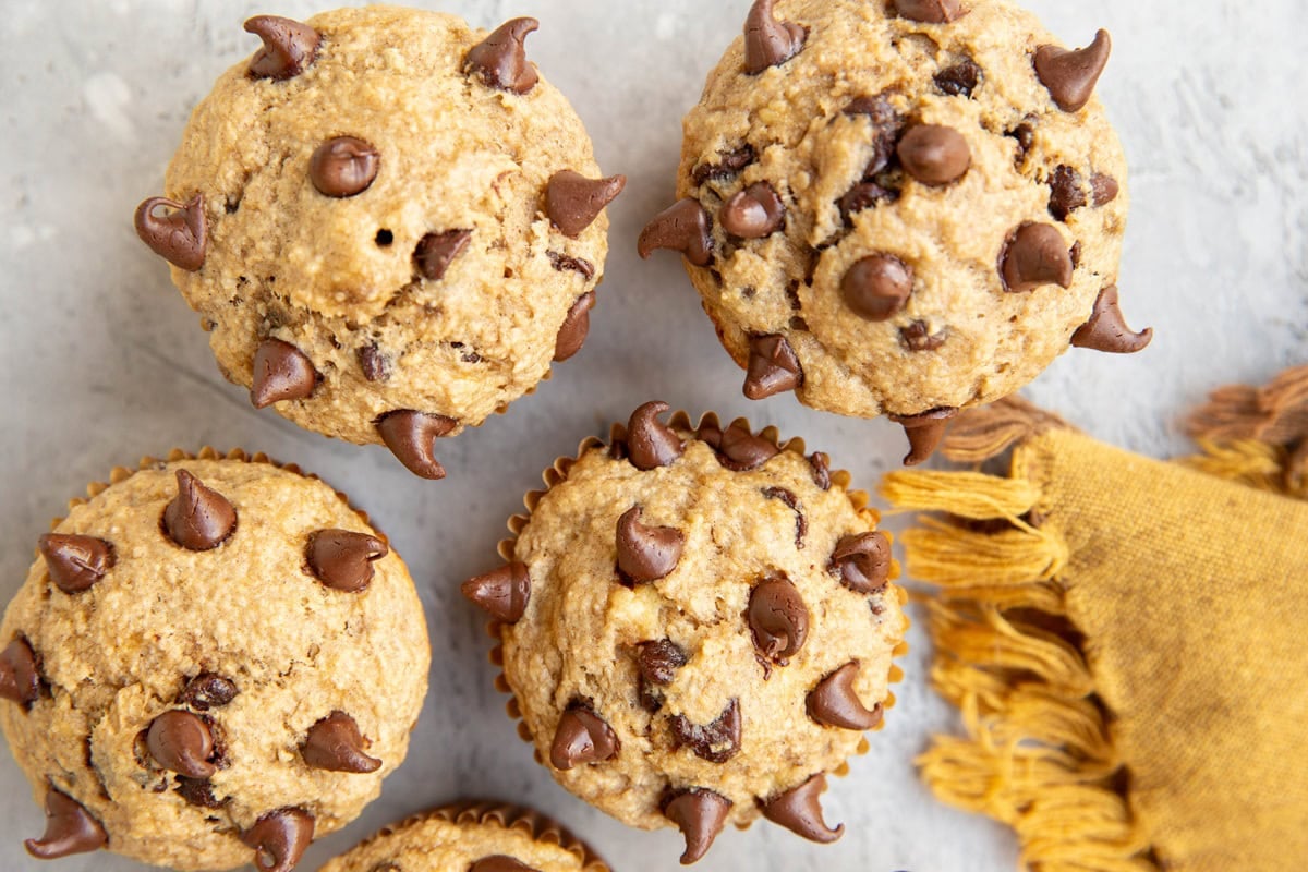 Chocolate chip banana oatmeal muffins on a surface, ready to eat.