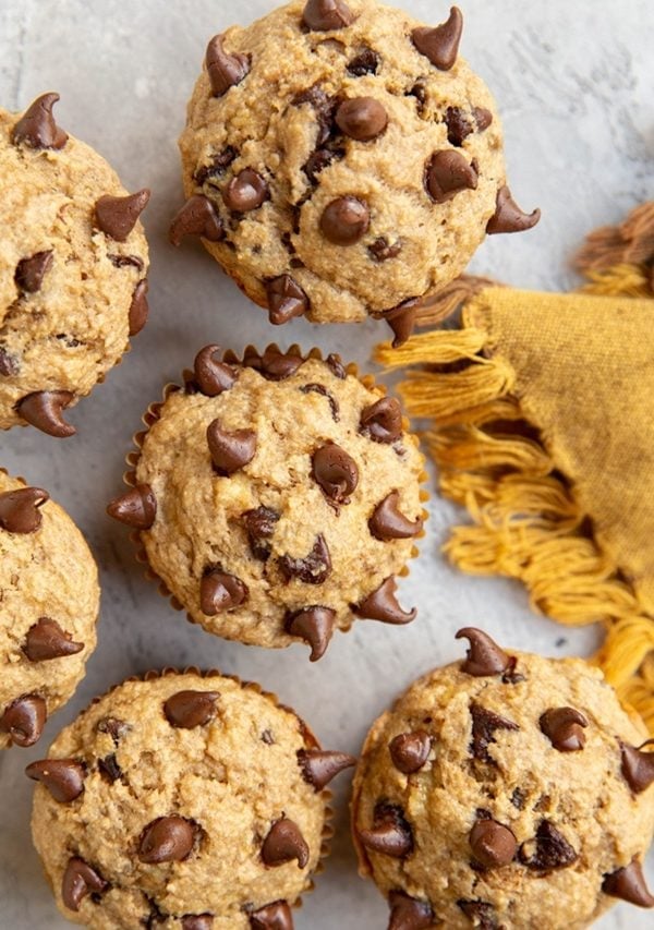 Banana oat muffins sitting on a background with a golden napkin to the side.