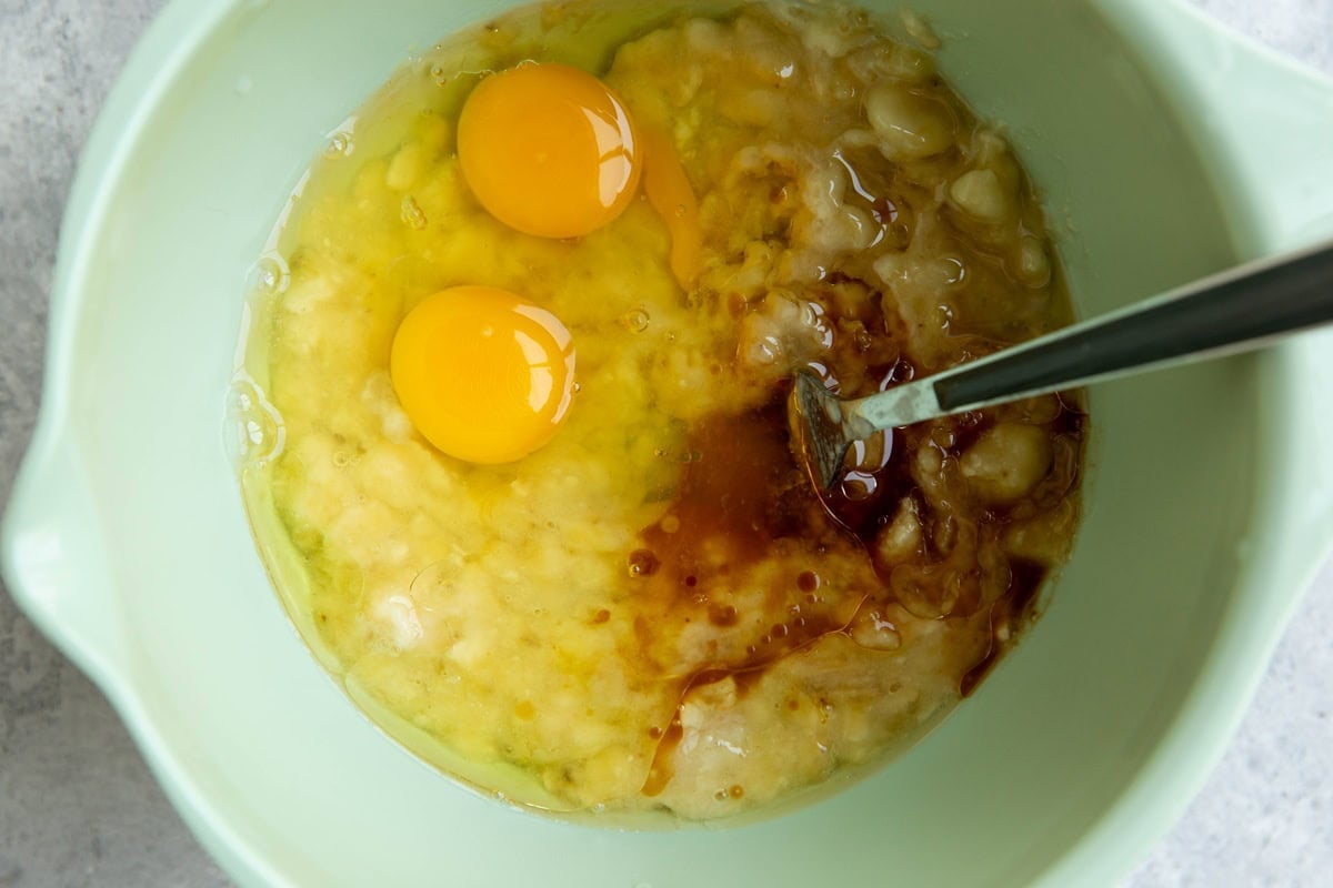 Mashed bananas, eggs, and vanilla extract in a mixing bowl, ready to be mixed together.