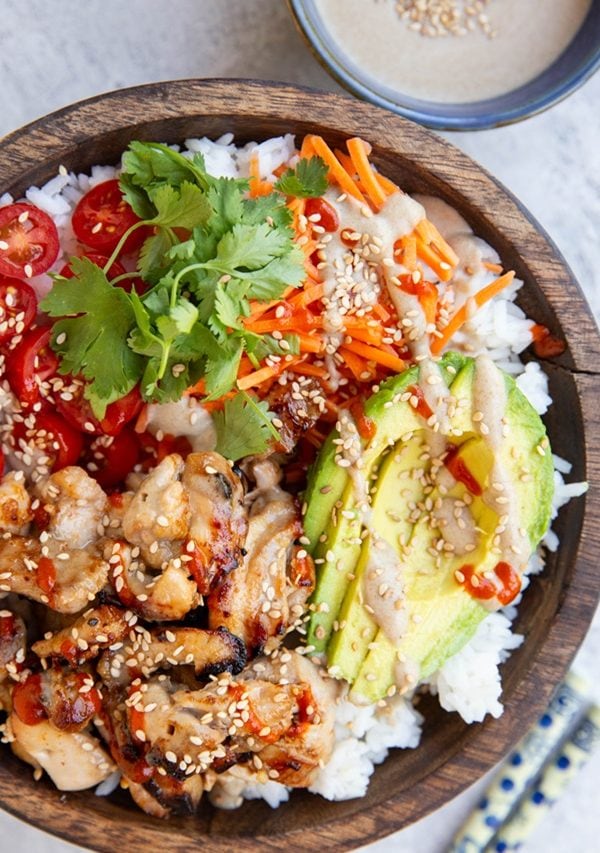 Bowl full of chicken satay, veggies, and rice with peanut sauce.