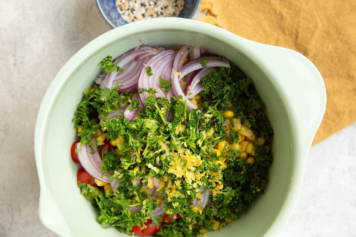 large mixing bowl full of ingredients for corn and tomato salad. Ready to be mixed together.