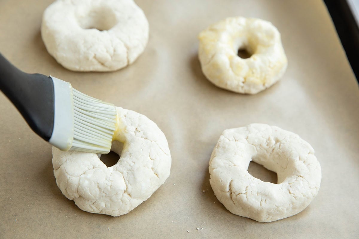 Brushing the bagels with egg wash with a silicone brush.