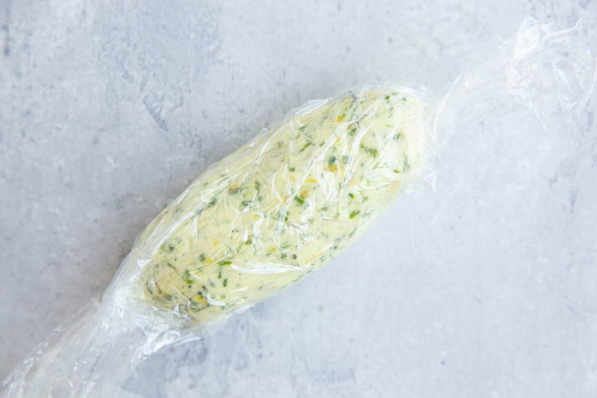 Compound butter wrapped up in a sheet of plastic wrap into a log shape.