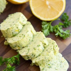 Garlic herb compound butter on a cutting board, cut into slices.