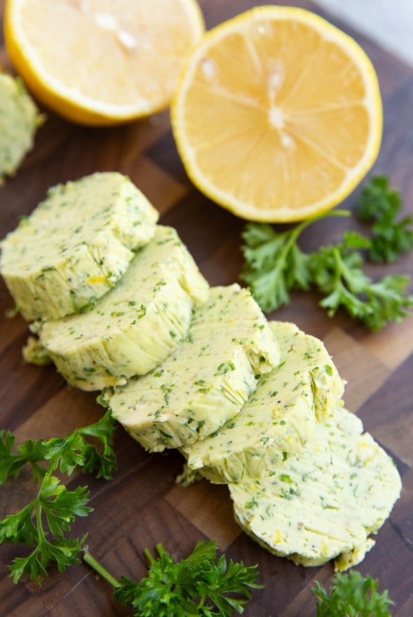 Garlic herb compound butter on a cutting board, cut into slices.