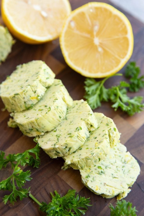 Garlic herb compound butter on a cutting board, cut into slices.