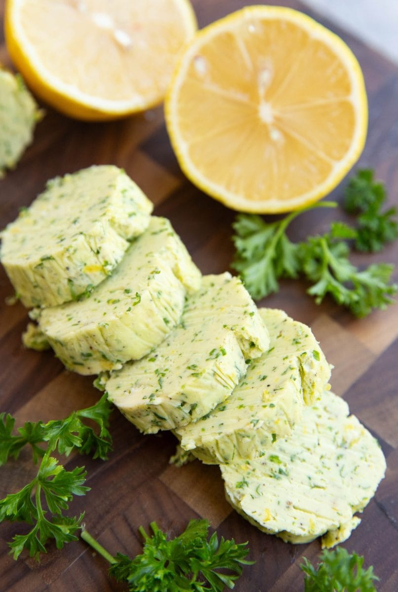 Garlic herb compound butter on a cutting board, cut into slices.