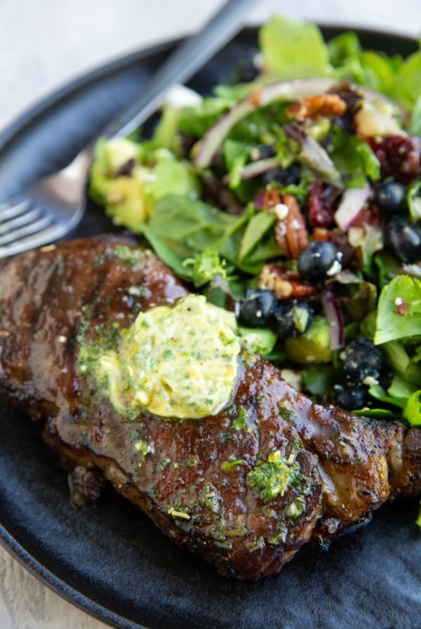 New York strip steak with a slice of compound butter on top, melting into the steak.