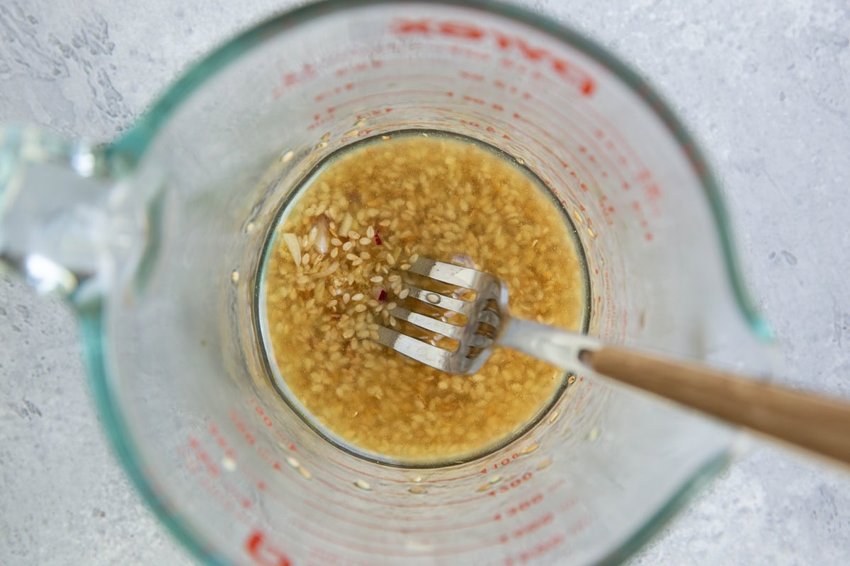Measuring cup with garlic ginger dressing for salad.