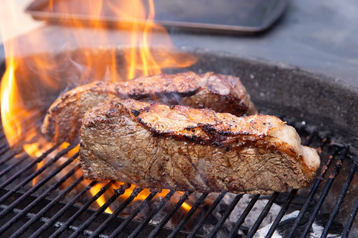 Steaks on their sides on a grill to grill the fat cap.