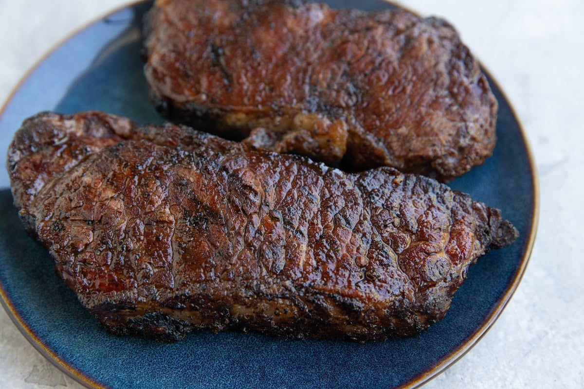 New York steaks on a plate, fresh off the grill and resting.