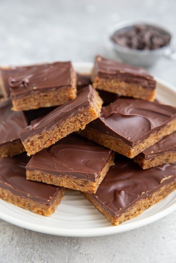 Stack of cookie dough protein bars on a plate with a chocolate layer on top.