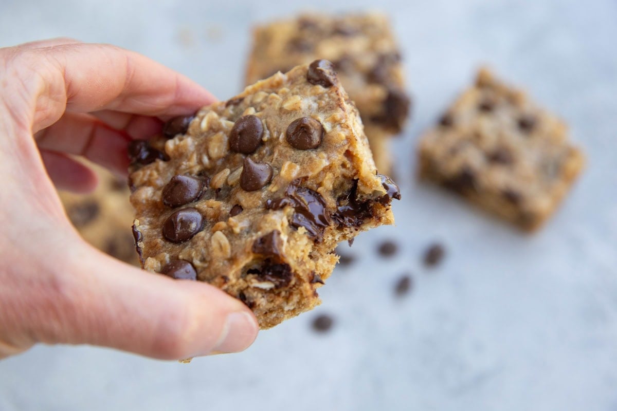 Hand holding a homemade protein bar with a bite taken out of it.
