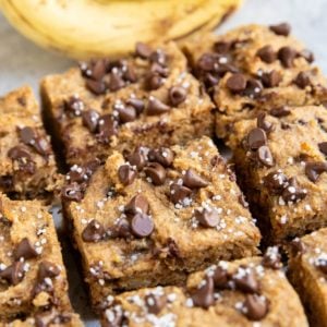 Almond flour banana bars cut into individual slices with fresh bananas in the background.