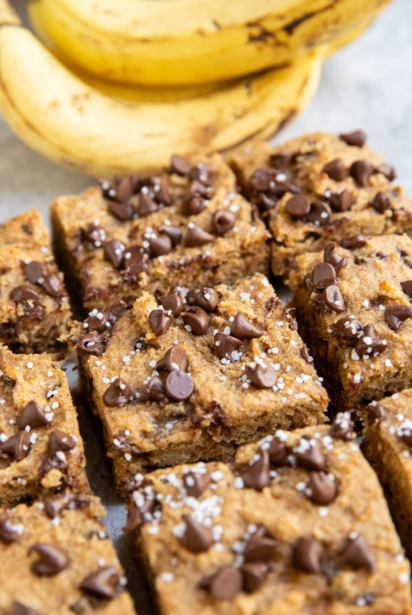 Almond flour banana bars cut into individual slices with fresh bananas in the background.