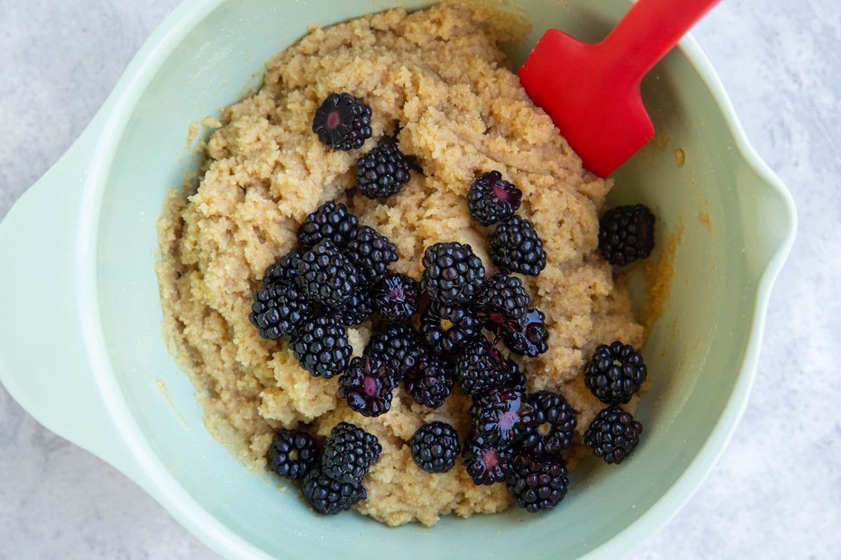 Mixing bowl full of scone dough with fresh blackberries on top, ready to be mixed in.
