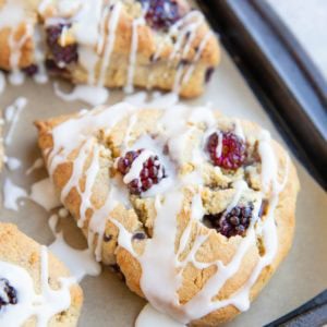 Baking sheet with blackberry almond flour scones drizzled with a simple glaze.