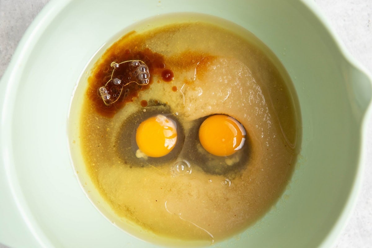 Applesauce, eggs, oil, pure maple syrup, and vanilla extract in a mixing bowl.