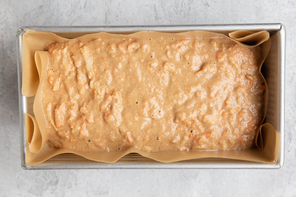 Loaf pan with carrot apple oat batter inside.