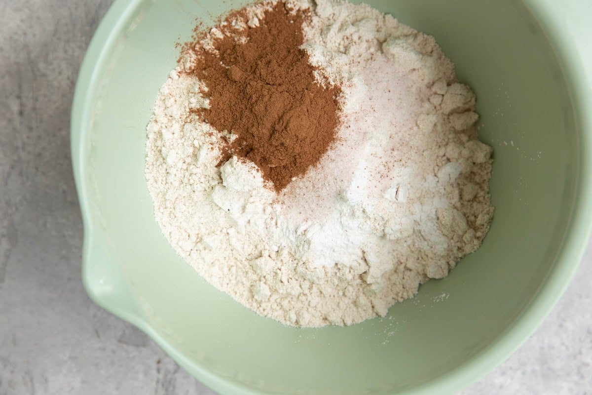Bowl full of oat flour, baking powder salt and ground cinnamon to make a quick bread.