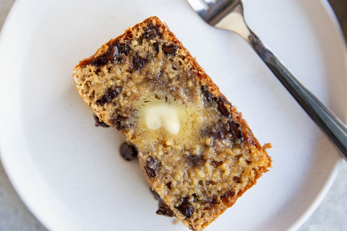 Slice of chocolate chip bread on a plate with melted butter on top.