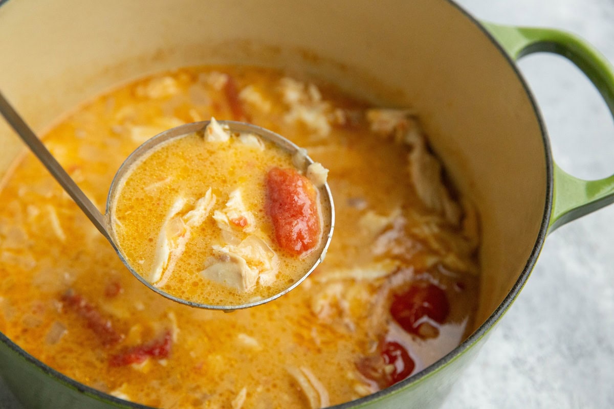 Large pot of fish soup with a ladle scooping some of the soup out.